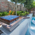 Custom water feature with built in fire bowl on inground swimming pool | Lafayette, LA
