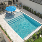 Stylish custom backyard pool with built-in umbrella, tanning ledge by Bask Pools in Lafayette, LA