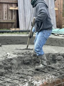 Gunite pool contractor shaping freshly sprayed gunite over steel rebar framework during a custom pool build in Lafayette, LA.