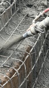 Gunite being sprayed from a high-pressure nozzle during custom pool construction by Bask Pools + Outdoors in Lafayette, LA