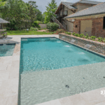 Custom-built inground pool with spa and water features by Bask Pools, a pool builder in Lafayette, LA