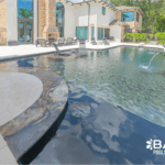 Complete pool renovation with fire and water feature, tanning ledge and modern finishes by Bask Pools – expert pool remodeler in Lafayette, LA